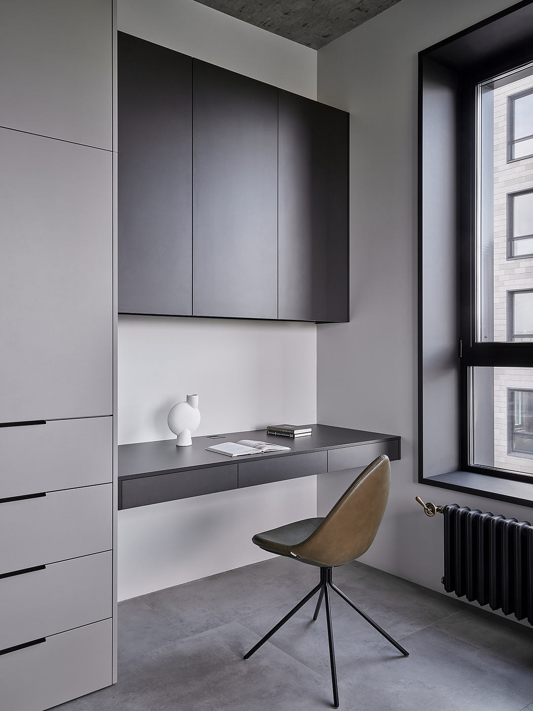 Monochromatic built-in cabinets and desk create a minimalist, modern workspace.