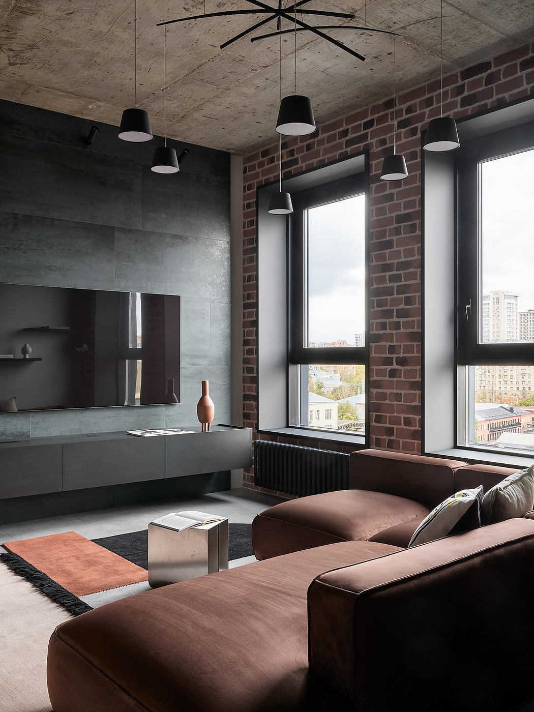 Minimalist living room with exposed brick walls, dark gray cabinetry, and pendant lighting.