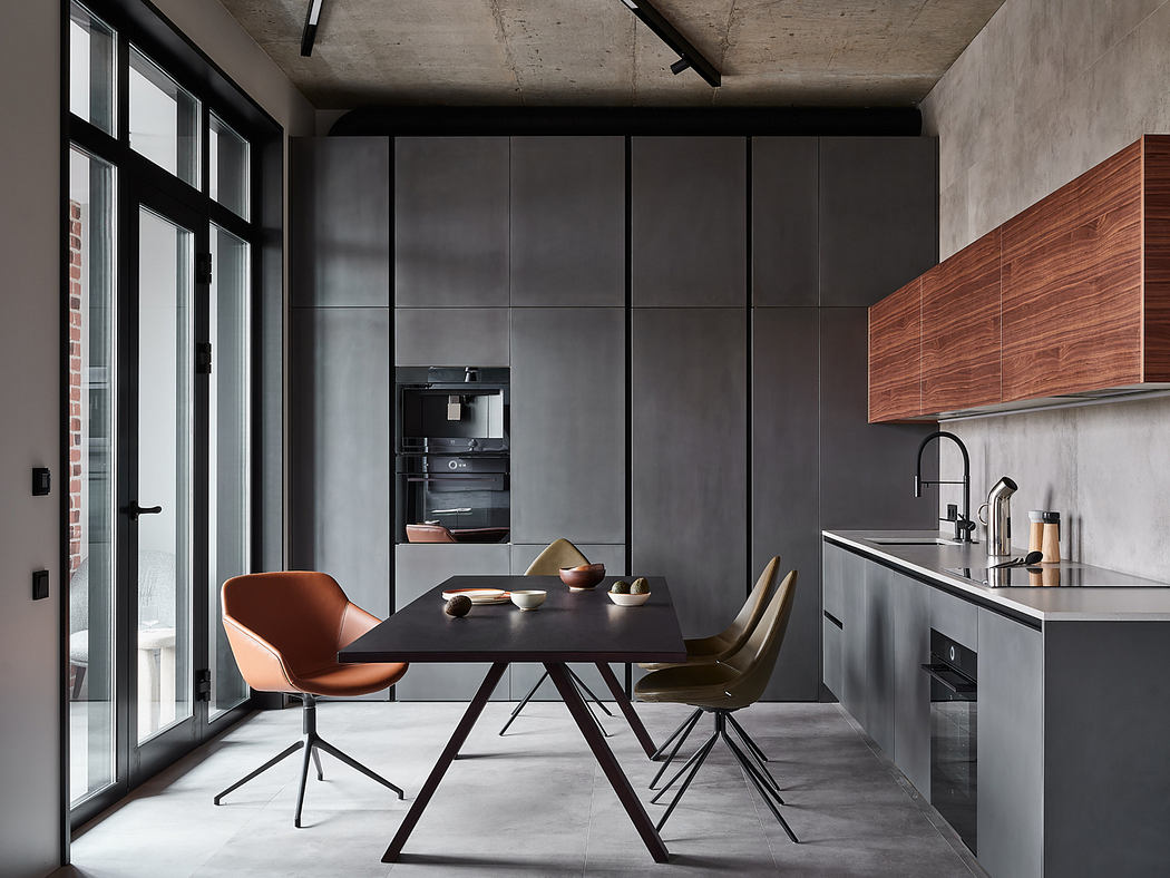 Modern industrial-style kitchen with concrete walls, dark-toned furniture, and large windows.