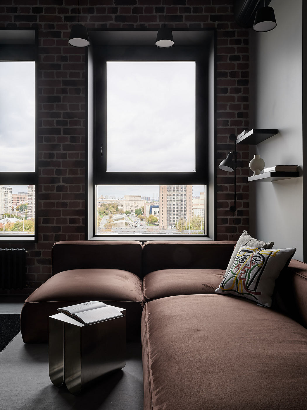 Cozy modern loft with exposed brick walls, large window overlooking cityscape.
