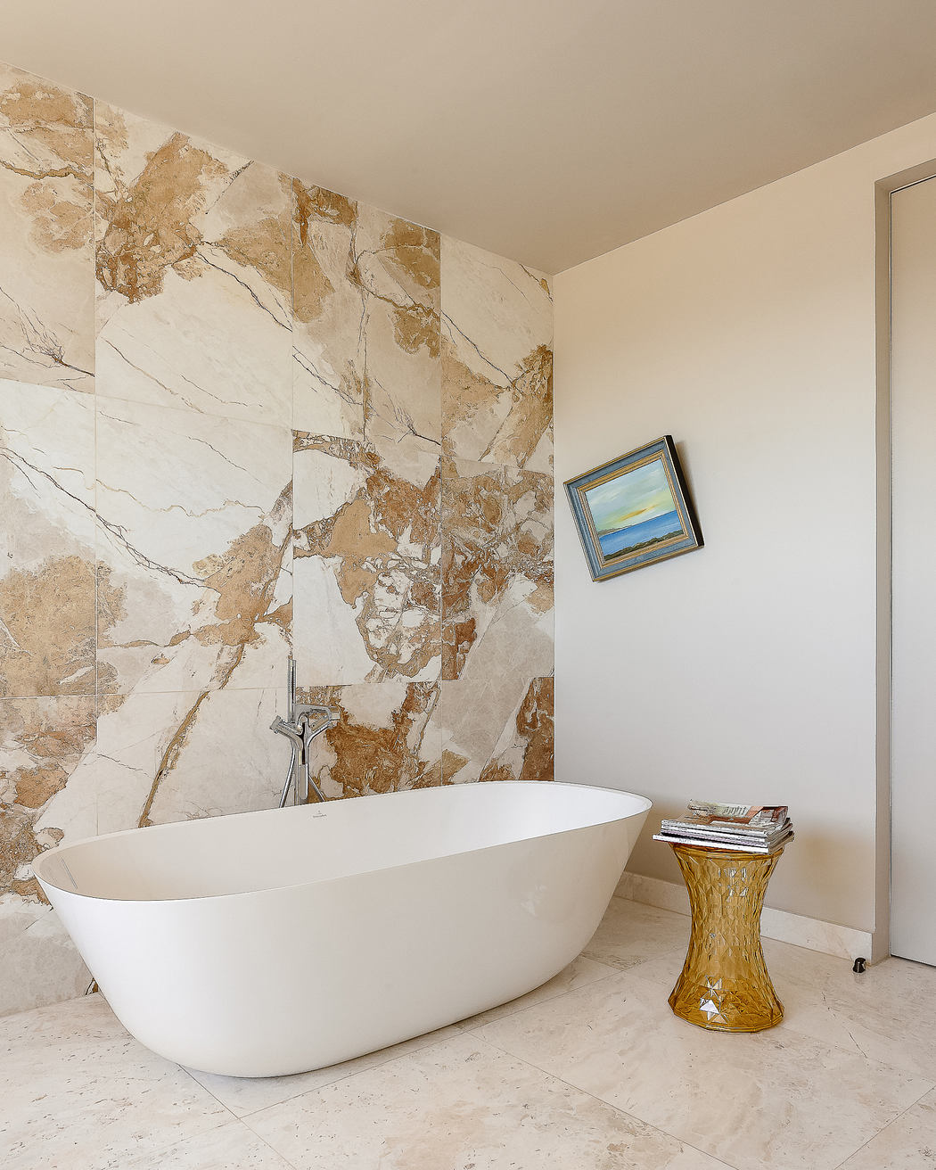 Luxurious bathroom with a freestanding white tub, marble-patterned walls, and a decorative side table.