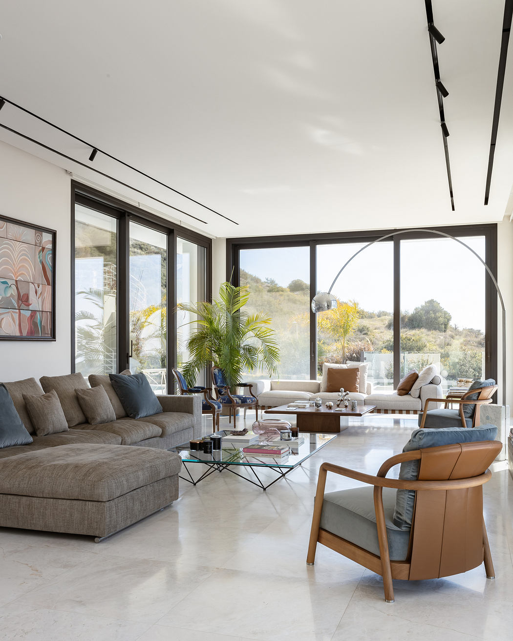 Spacious, open-concept living room with floor-to-ceiling windows, modern furniture, and lush decor.