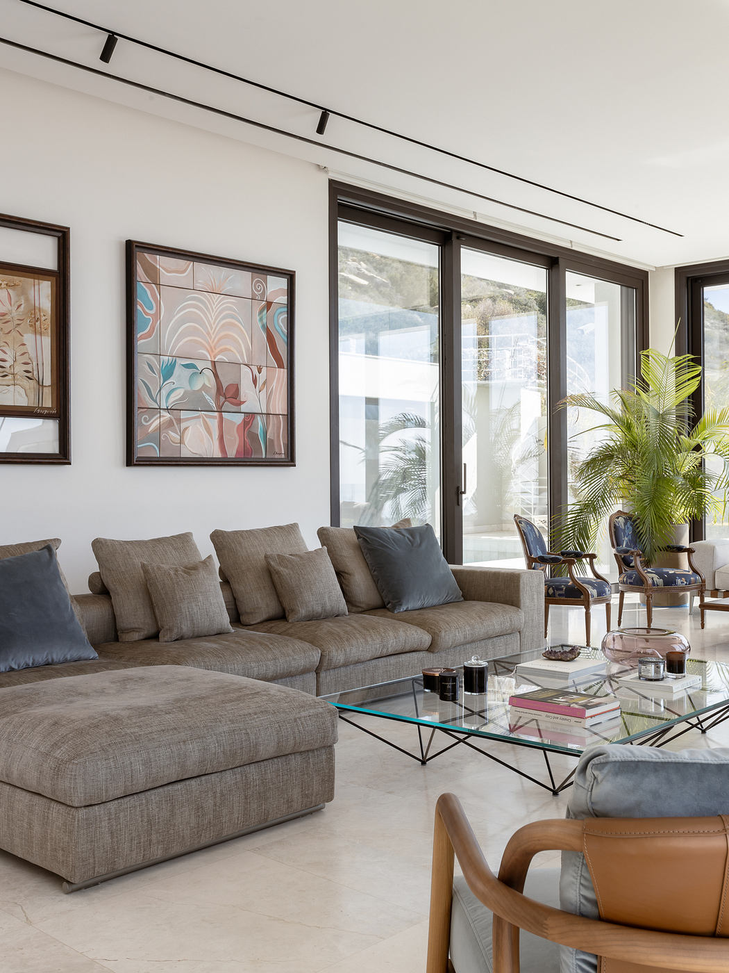 Spacious living room with large windows, modern furniture, and abstract wall art.