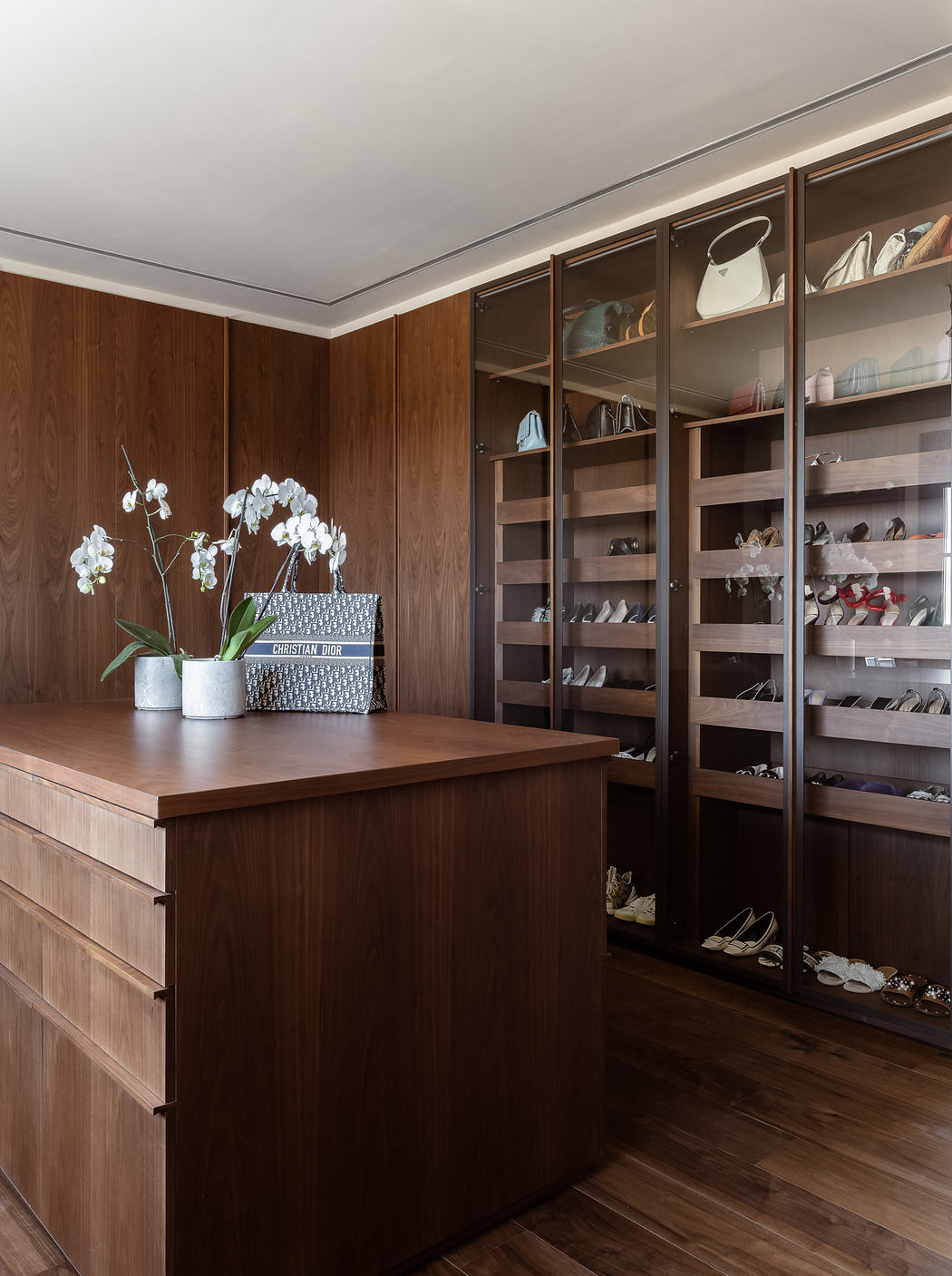 Elegant wooden closet with display shelves and a central dresser table adorned with flowers.