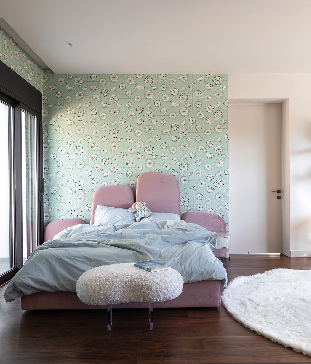 Cozy bedroom with plush pink furniture, floral wallpaper, and soft furnishings.