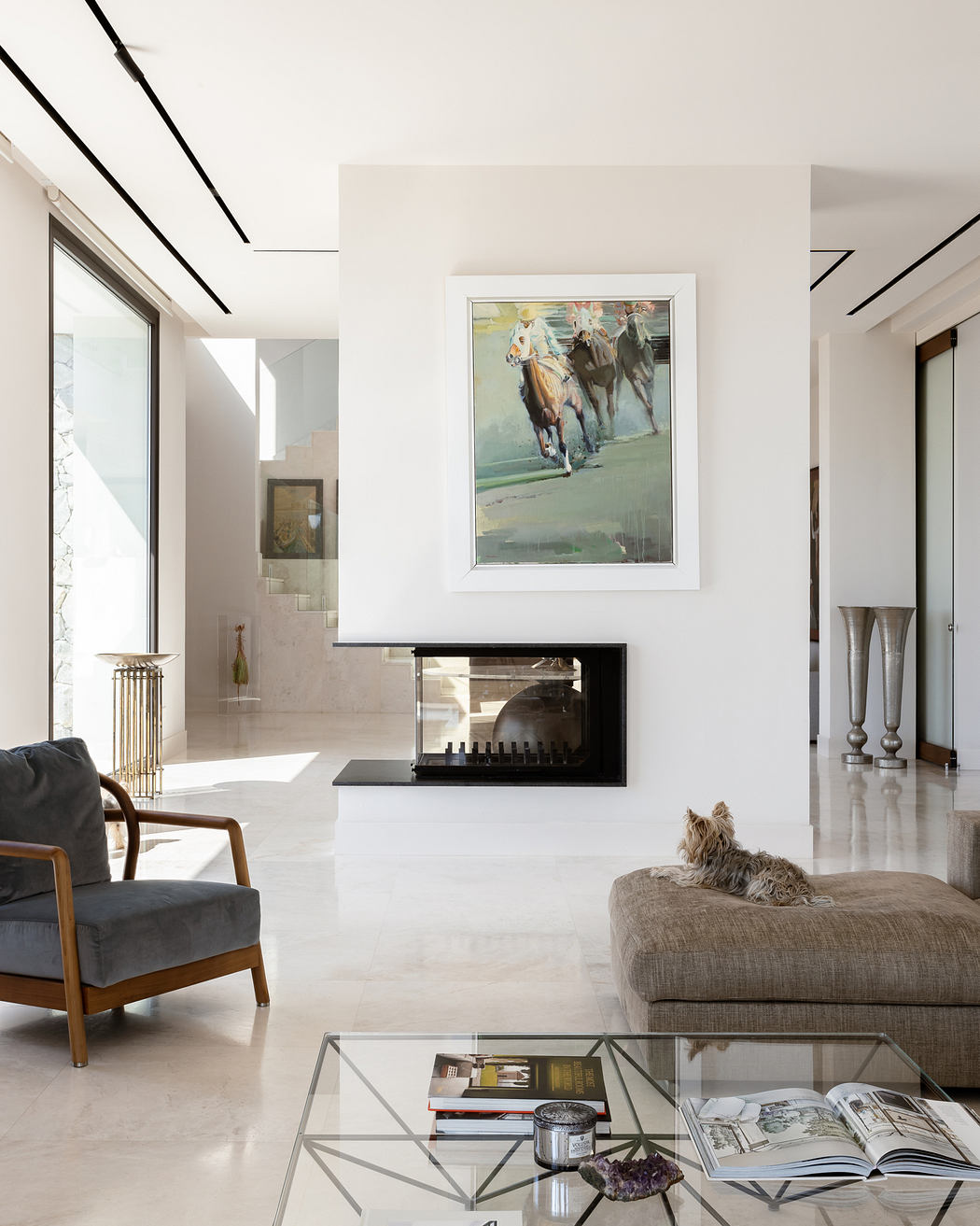Elegant, minimalist living space with modern fireplace, art, and a cozy dog companion.