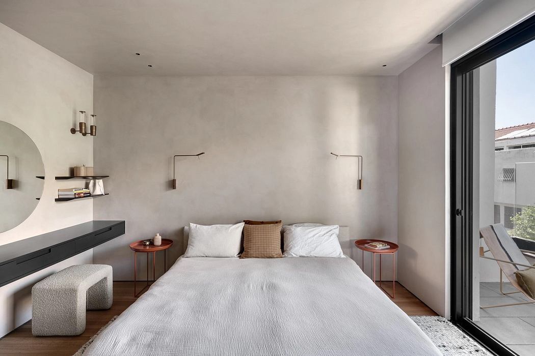 Minimalist bedroom with modern furniture, warm lighting, and large window offering view.