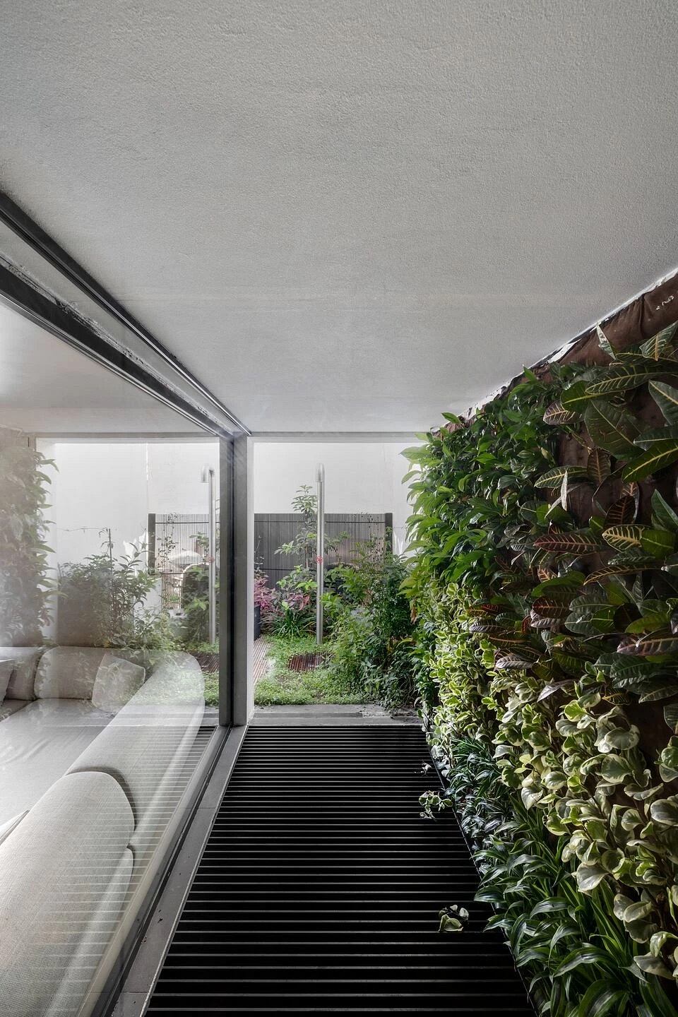 A modern interior design with a lush, verdant indoor garden and large glass windows overlooking it.