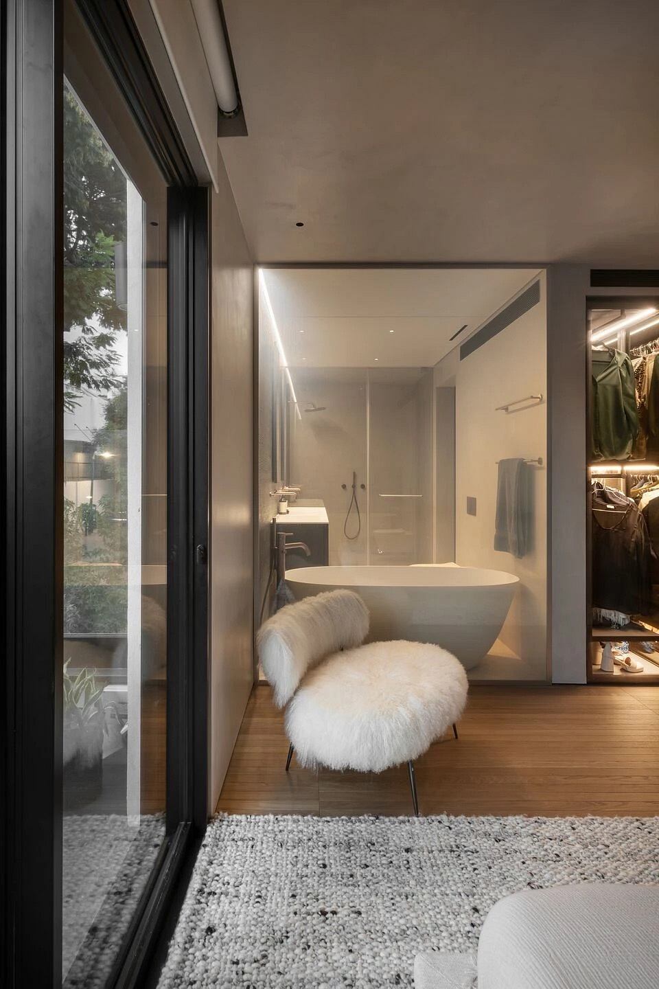 Luxurious modern bathroom with freestanding tub, plush seating, and large windows.