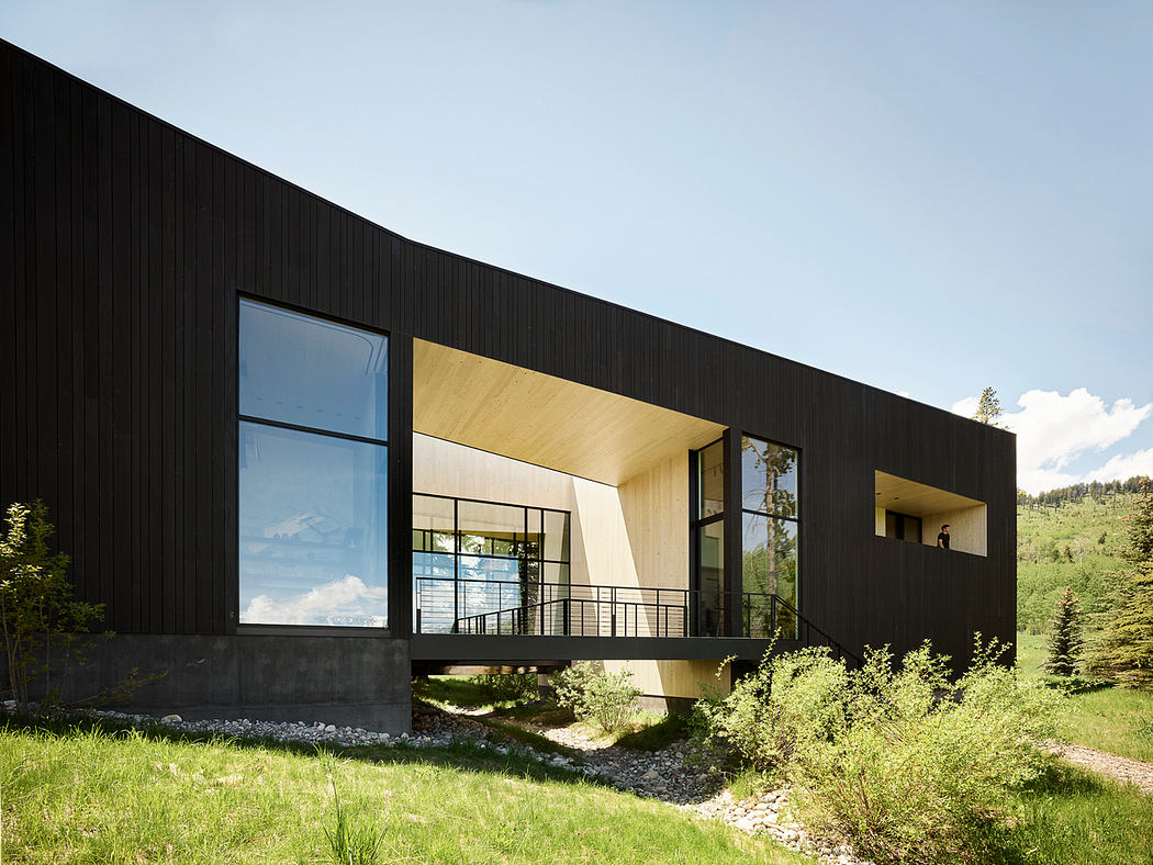 Modern architectural design with black wooden exterior, large windows, and cantilevered balconies.