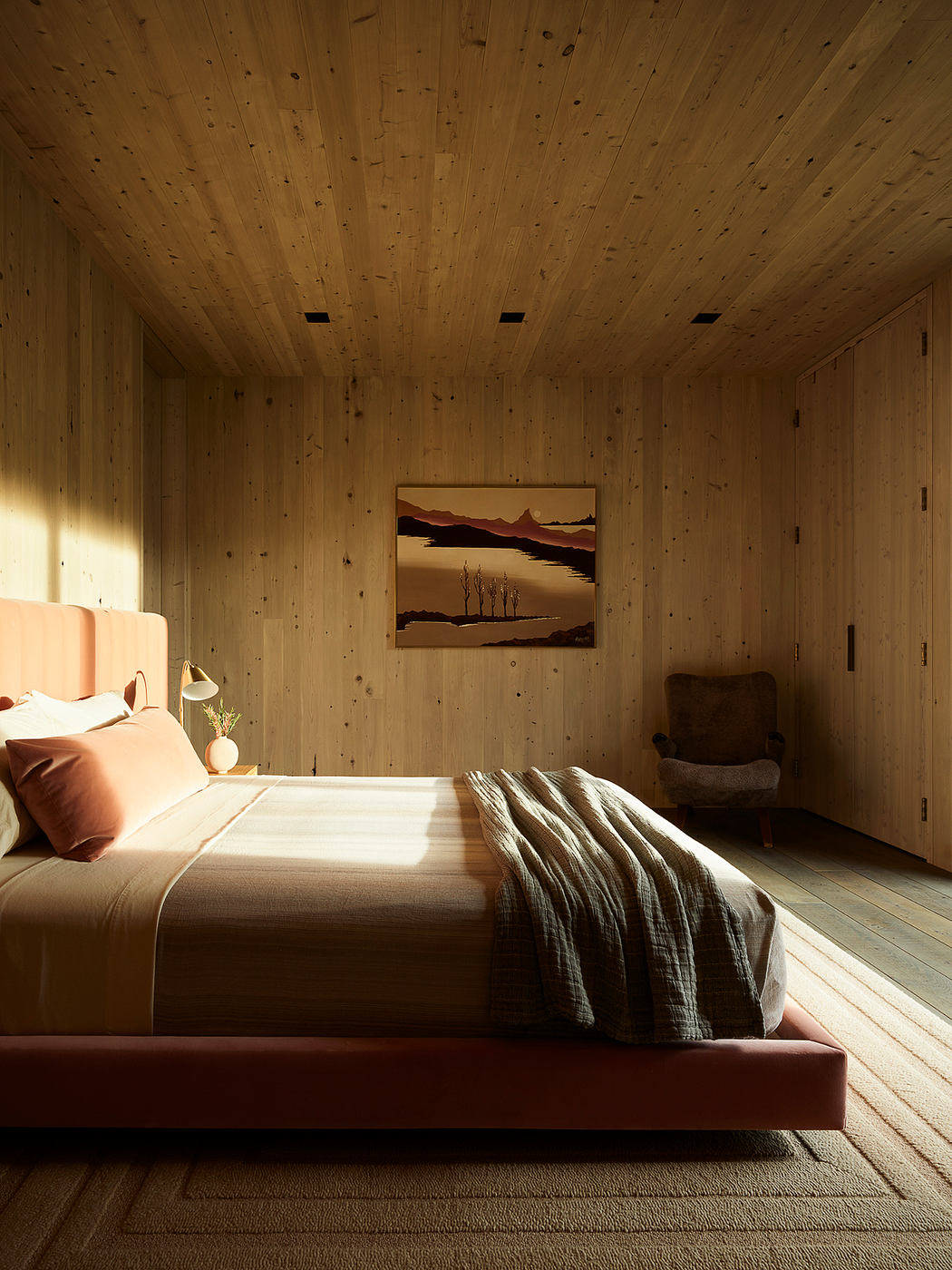 Cozy wood-paneled bedroom with landscape painting and warm lighting creates a serene atmosphere.