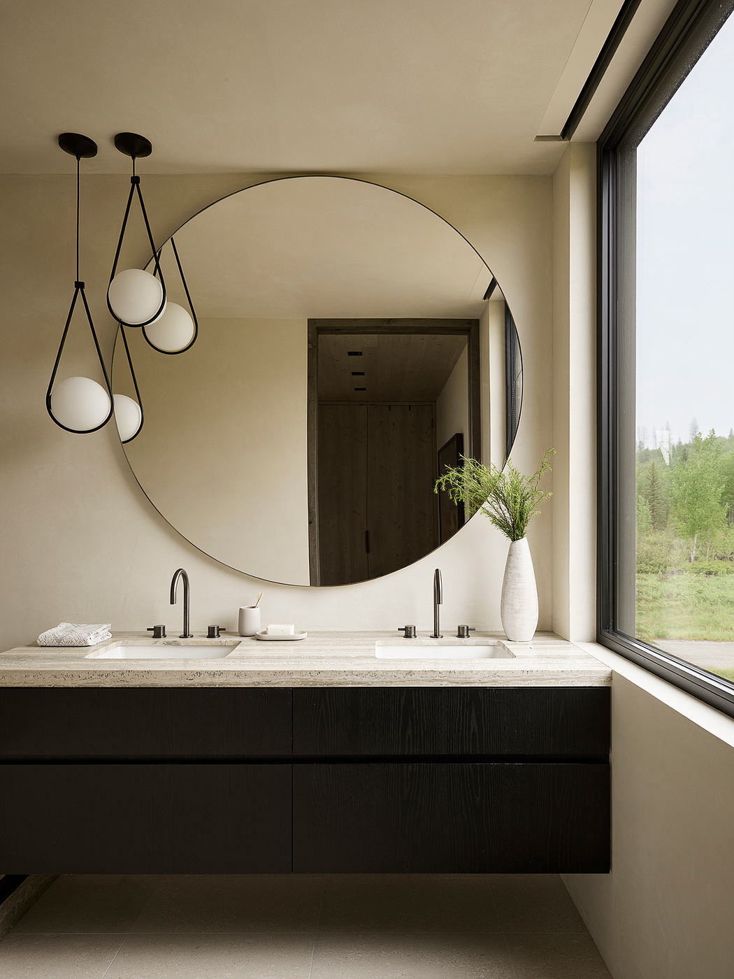Minimalist bathroom with a large round mirror, dark wood vanity, and panoramic window.