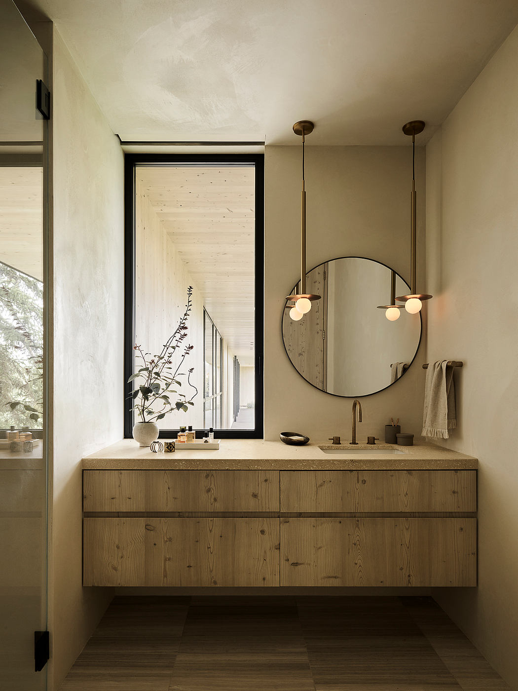 Elegant vanity with wooden drawers, round mirror, and pendant lighting in modern bathroom.