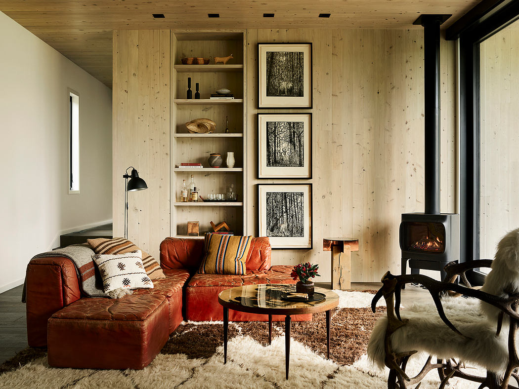 Rustic wooden cabin interior with leather sofa, shelving, and framed forest artwork.