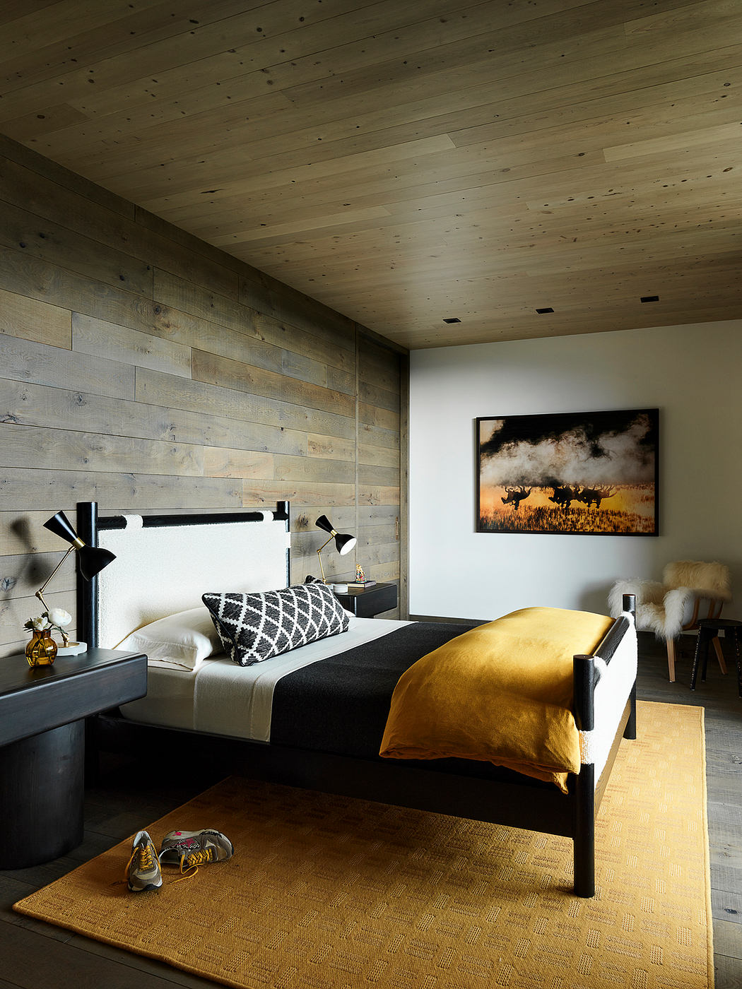 Warm, rustic bedroom with wooden walls, plush textures, and a striking wildlife painting.