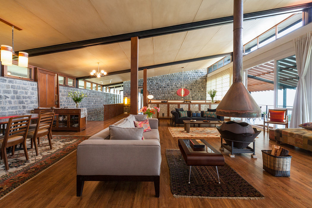 Rustic, open-concept living space with stone walls, wooden beams, and an assortment of furniture.