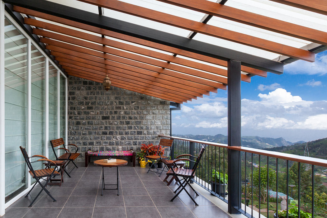Covered patio with wooden beams, brick walls, and glass railing overlooking mountain view.