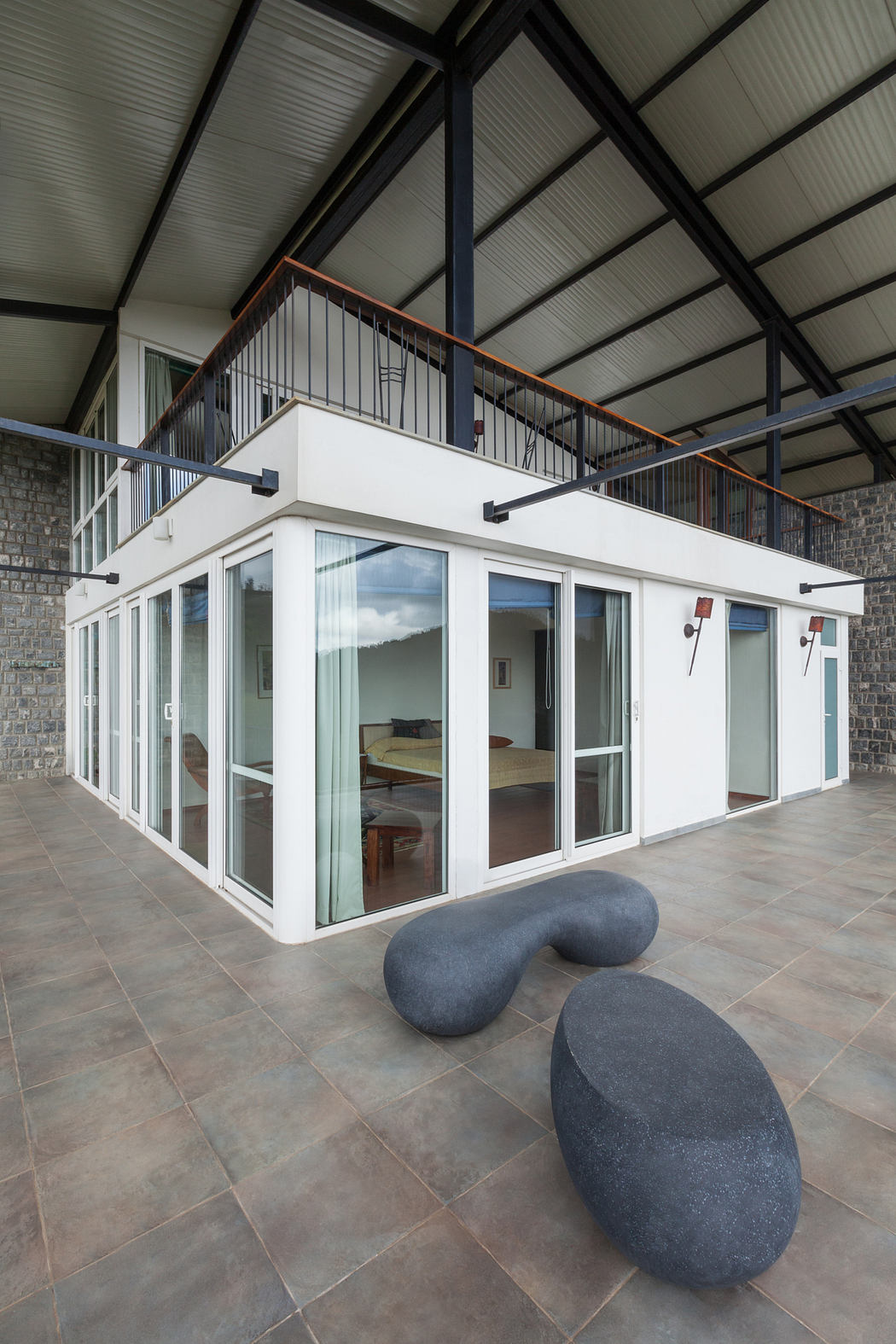 A modern architectural design with large glass walls, metal beams, and sculptural stone features.