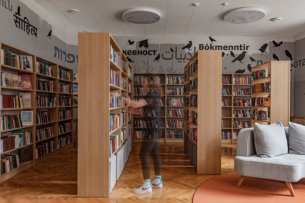 A modern library interior with wooden bookshelves, colorful artwork, and a cozy seating area.