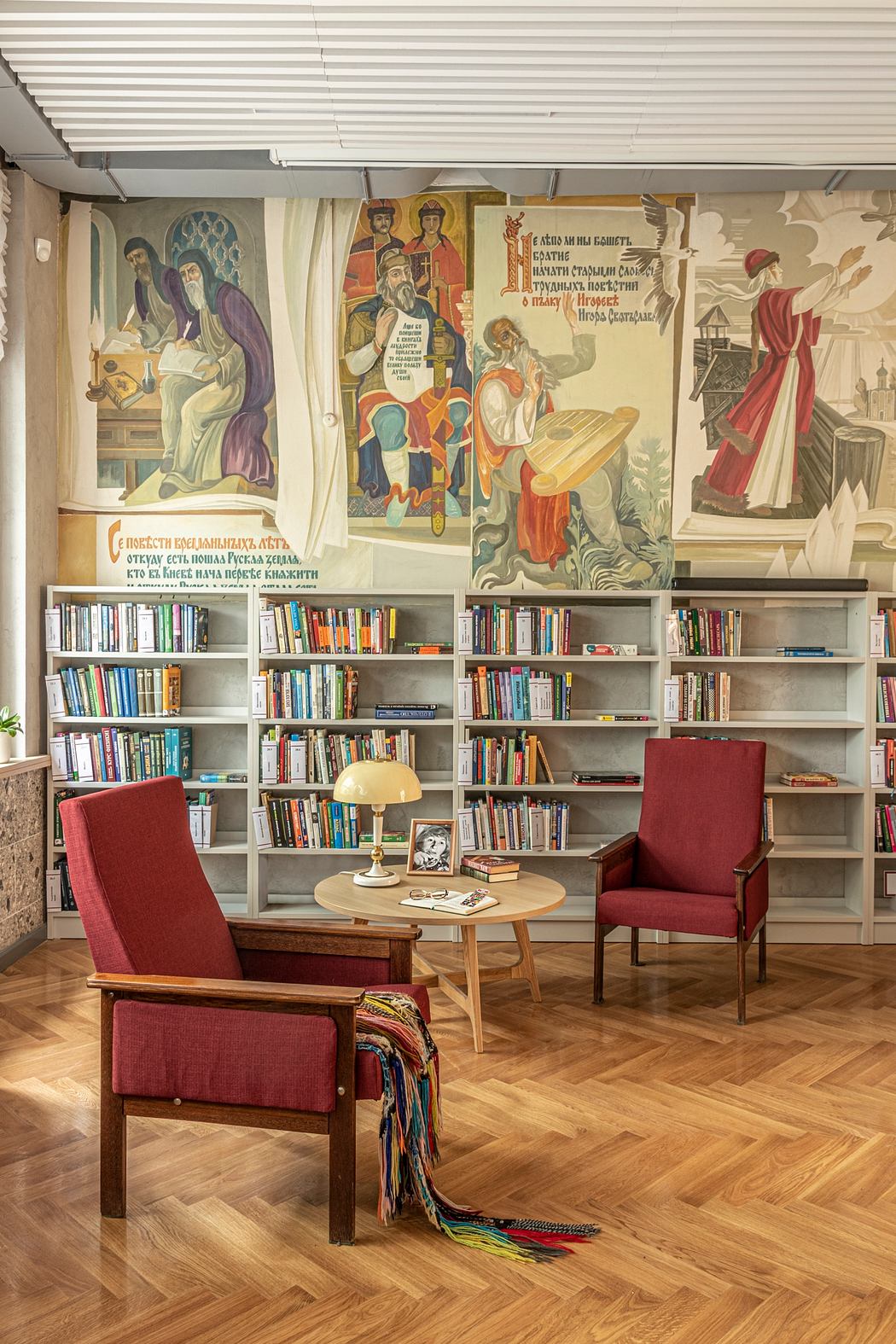 Cozy library nook with built-in bookcases, vibrant wall murals, and comfortable seating.