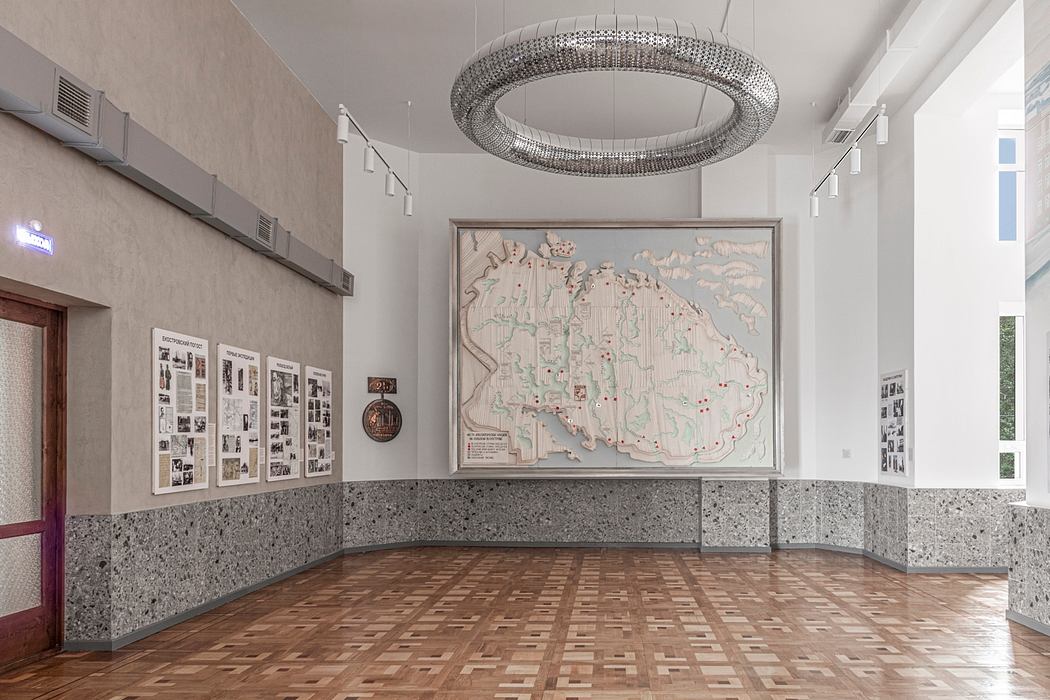 Spacious room with detailed terrazzo flooring, circular chandelier, and framed map artwork.