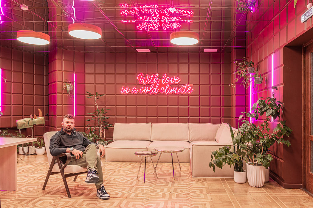 A vibrant, neon-lit space with geometric tiling, plush seating, and lush greenery.