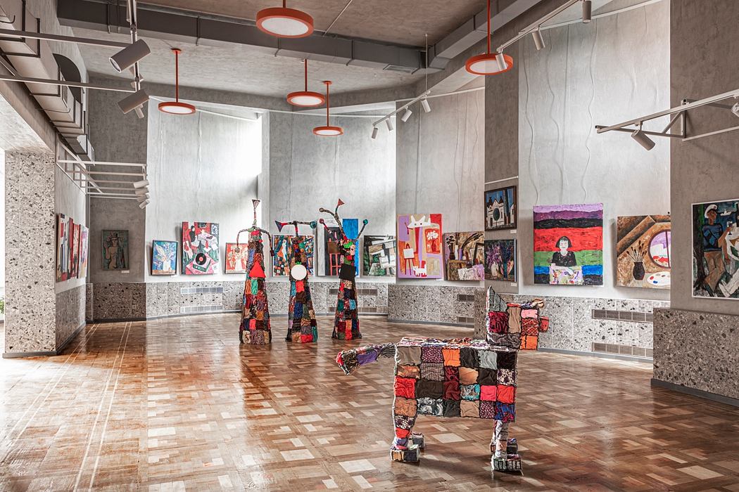 Spacious art gallery with colorful abstract sculptures, paintings, and patterned furniture.