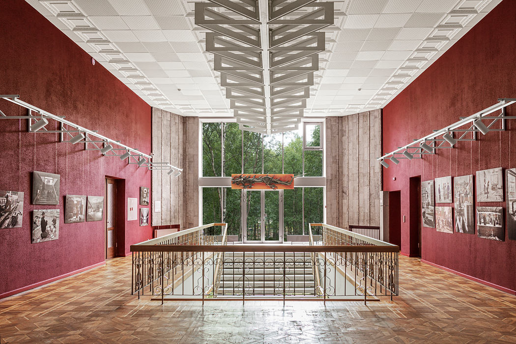 Striking architectural design with vibrant red walls, ornate railings, and natural light.