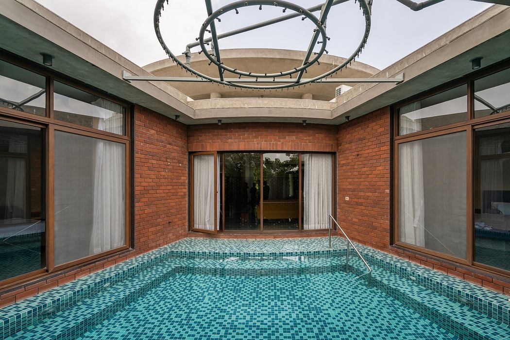 Striking indoor pool surrounded by brick walls and glass windows, featuring a unique overhead lighting fixture.