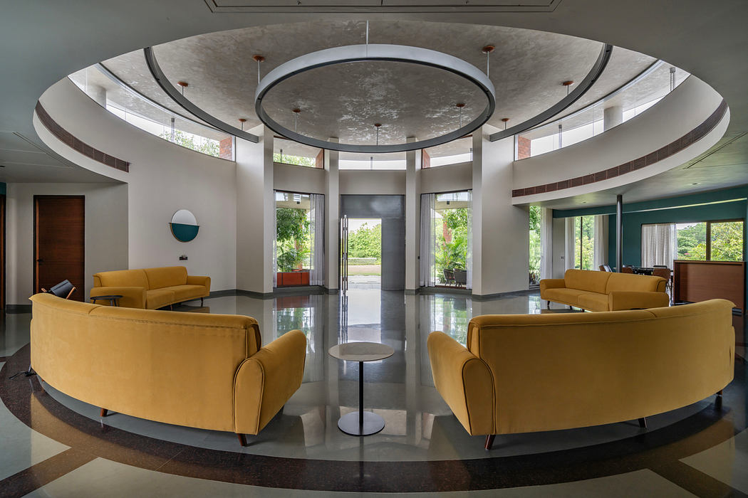 Sleek, modern lobby with curved ceiling, circular lighting, and plush yellow seating.