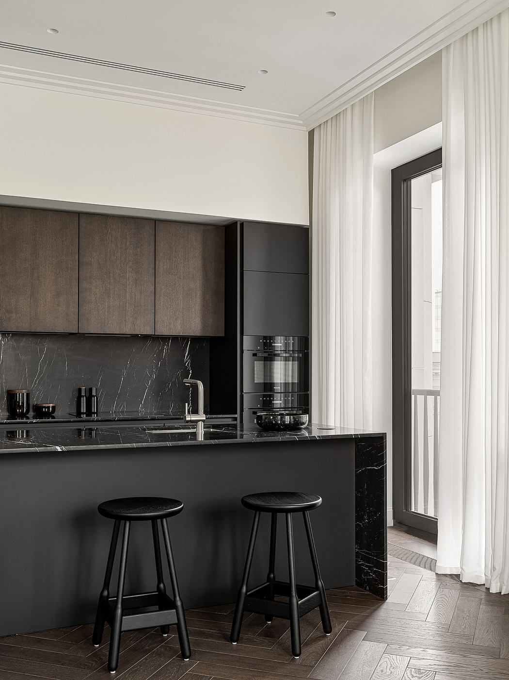 Sleek, modern kitchen with dark wood cabinetry, black marble countertops, and minimalist bar stools.