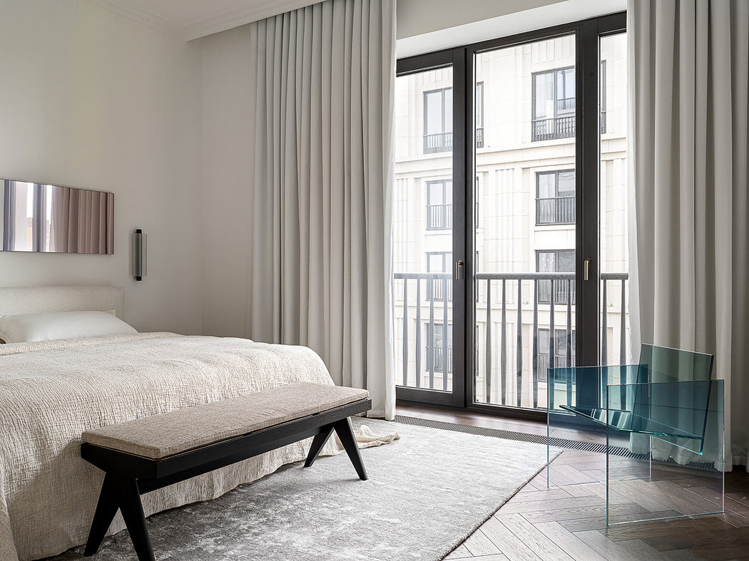 Spacious modern bedroom with large windows, plush bedding, and minimalist furnishings.