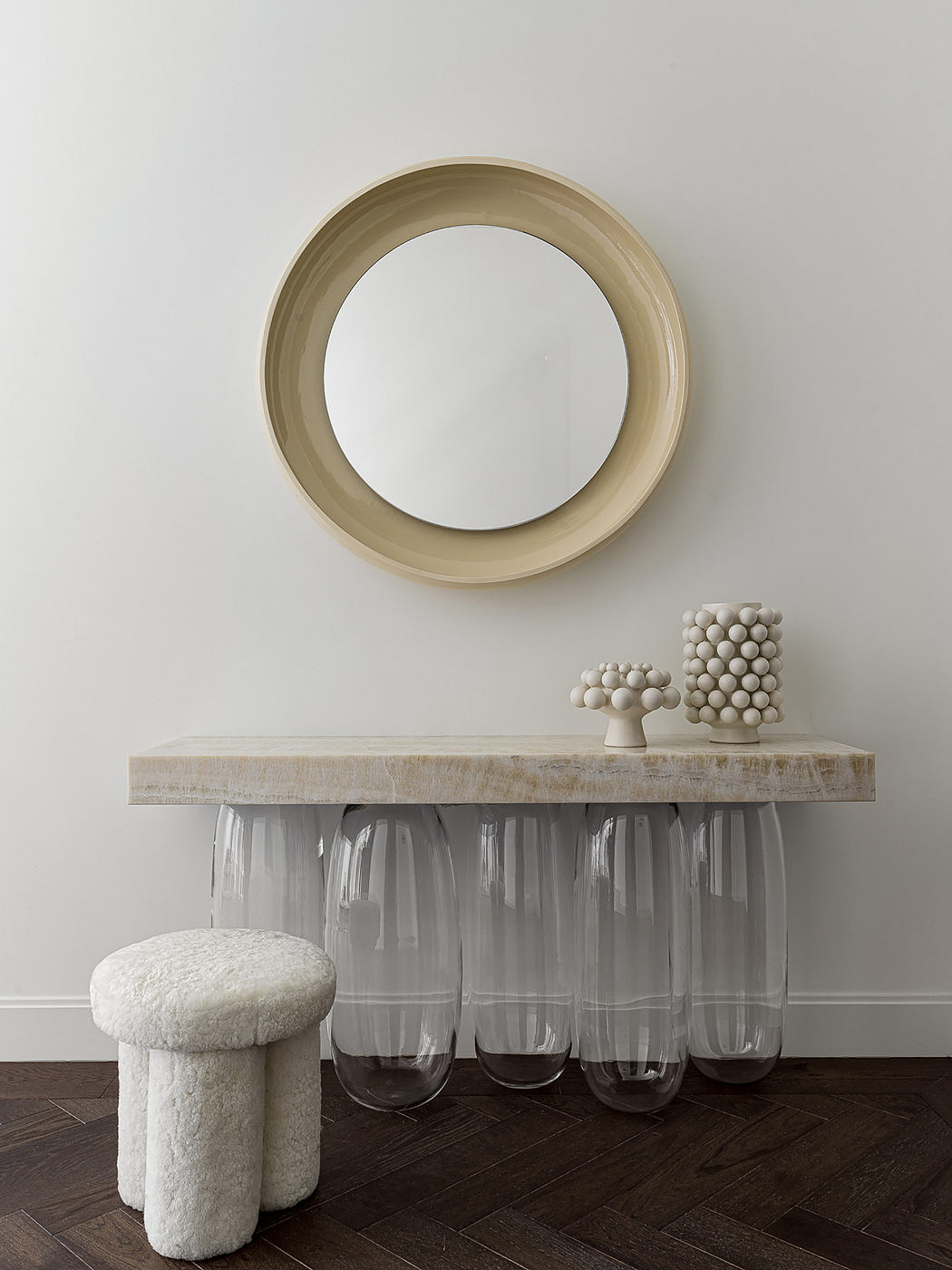 Minimalist interior design with a round mirror, wooden console table, and decorative spheres.