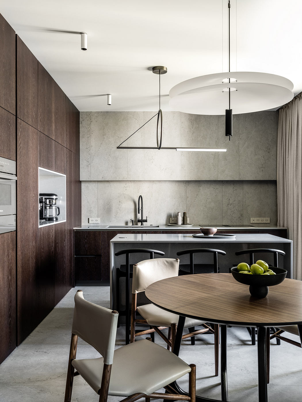 A modern kitchen with a wood-paneled wall, sleek appliances, and a round dining table with chairs.