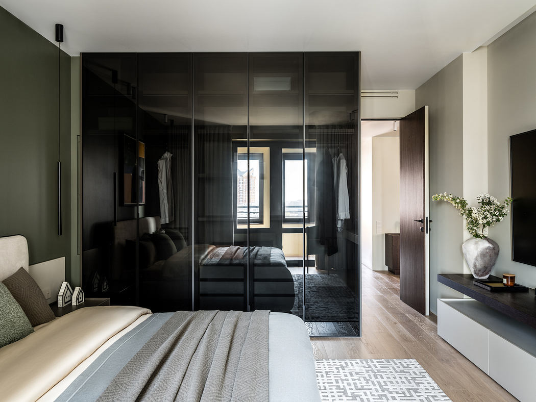 Sleek, modern bedroom with floor-to-ceiling mirrored closets, minimalist decor, and large windows.