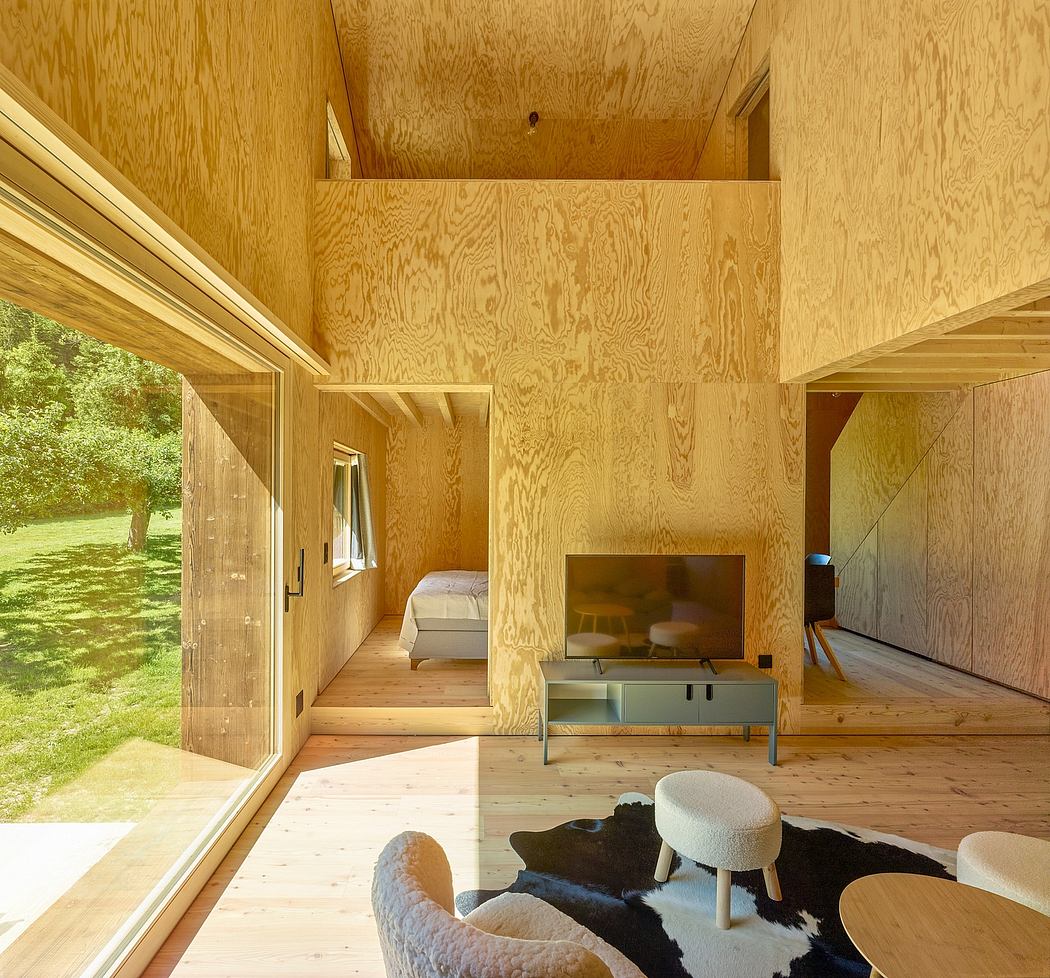 An airy, wood-paneled interior with large windows overlooking a lush outdoor scene.