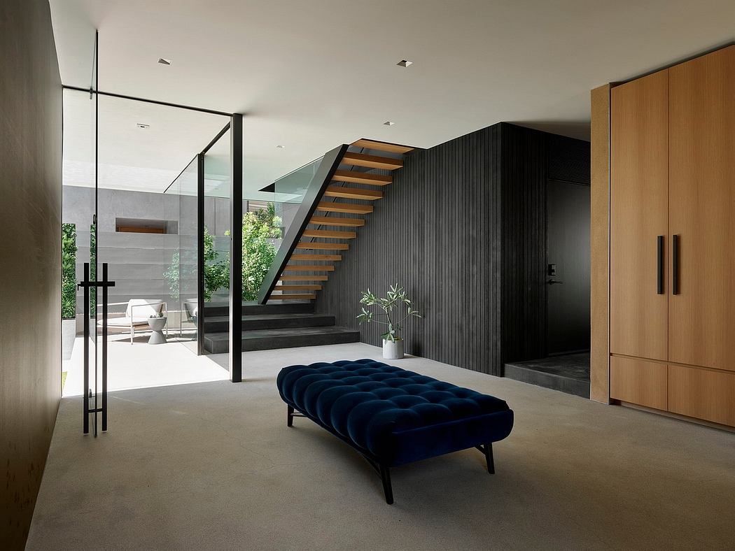 A modern interior with a sleek staircase, dark wood cabinets, and a plush navy blue sofa.