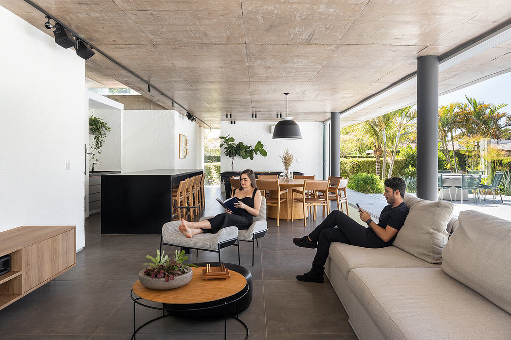 Spacious modern open-plan living area with concrete ceiling, wooden furnishings, and greenery.