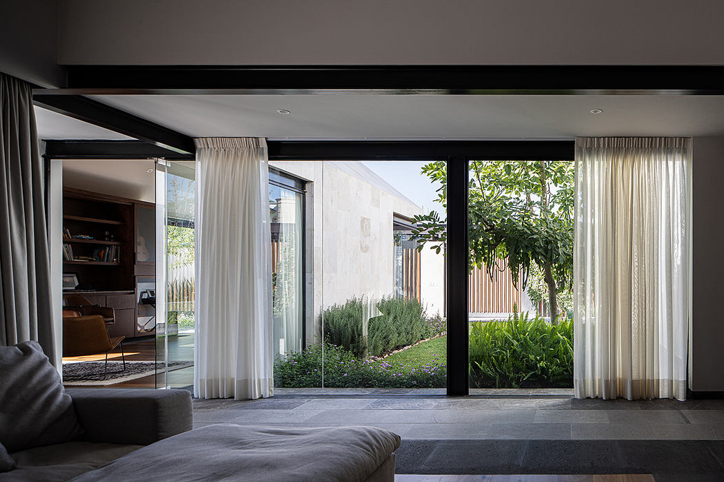 Elegant modern interior with large glass doors overlooking lush garden landscape.