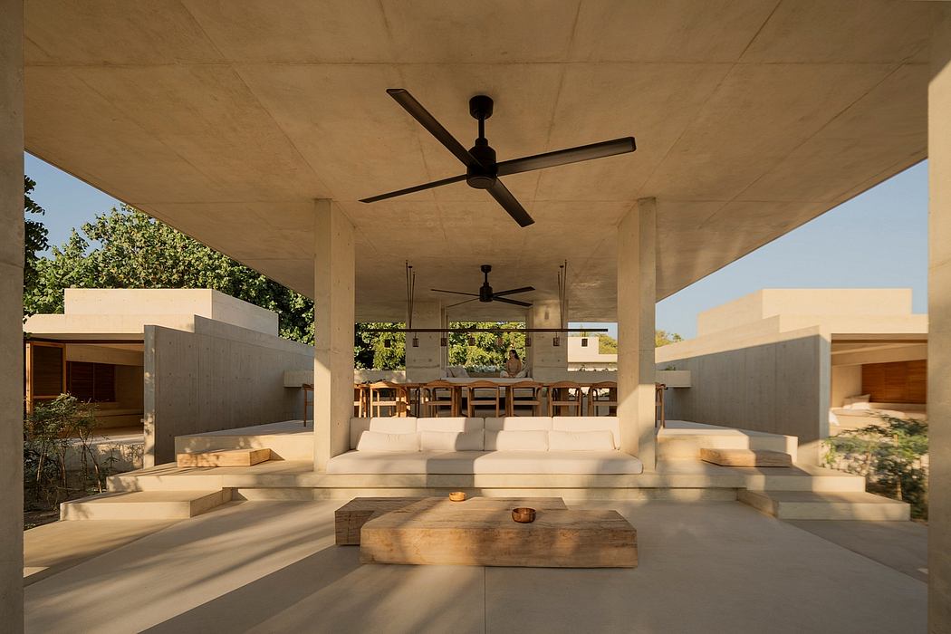 Covered outdoor seating area with modern, minimalist furnishings and overhead fans.