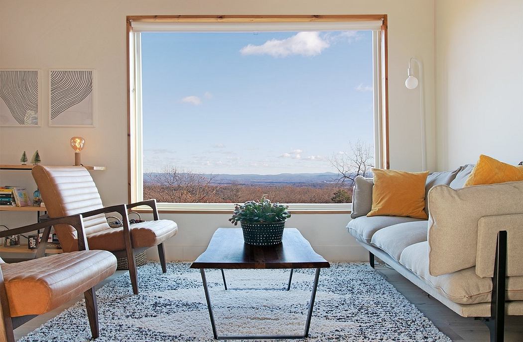 Warm, cozy living room with large windows framing a scenic mountain view and modern furniture.