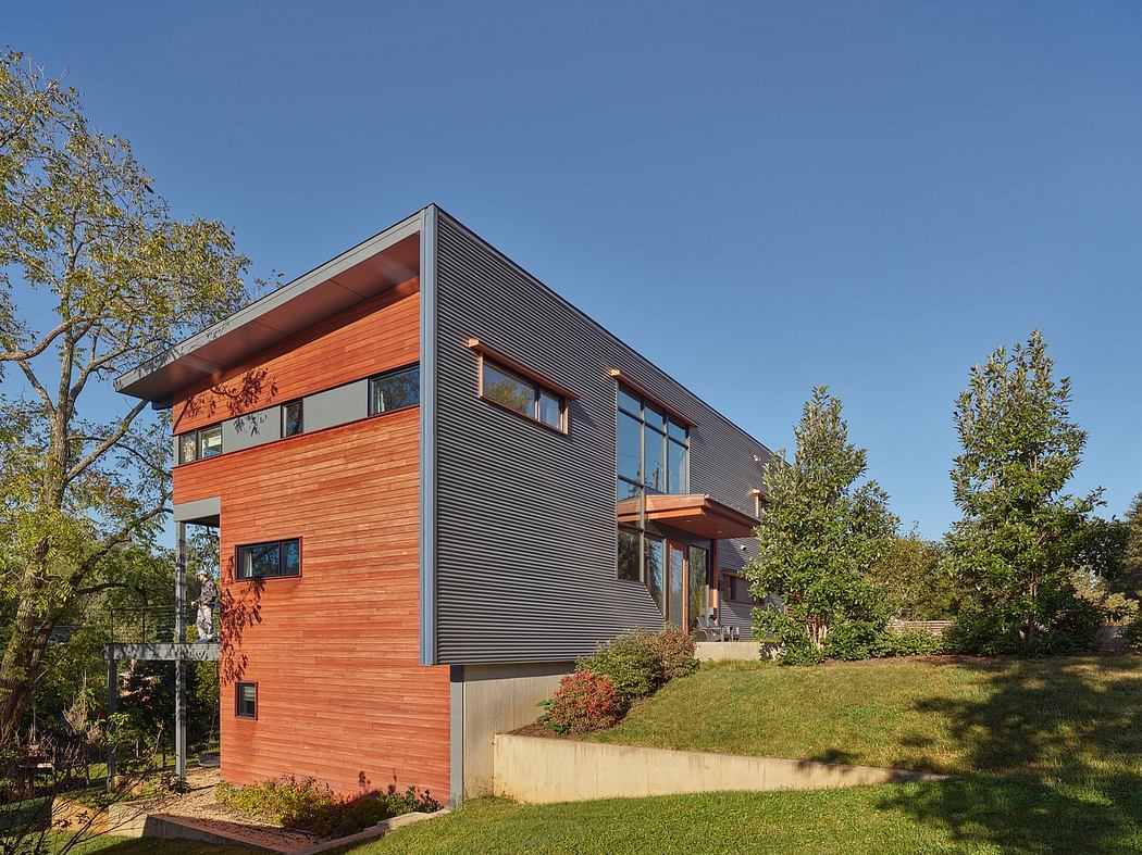 A modern two-story home with a mix of wood and metal siding, set in a lush, green landscape.