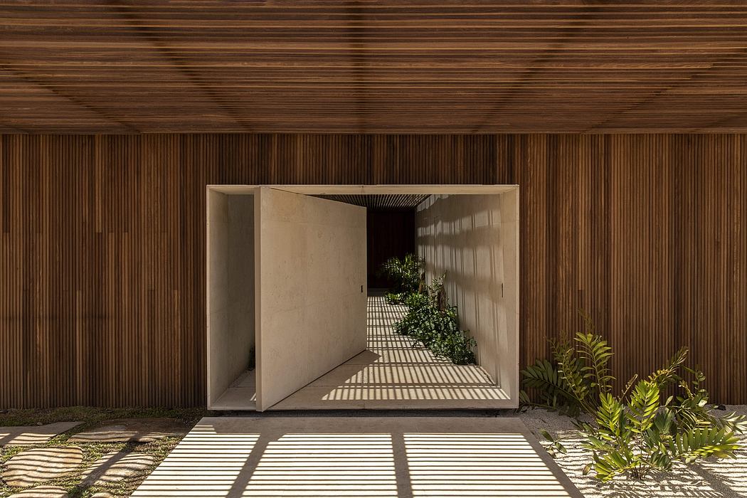 A wood-paneled exterior with a recessed, open-air entryway and lush greenery inside.