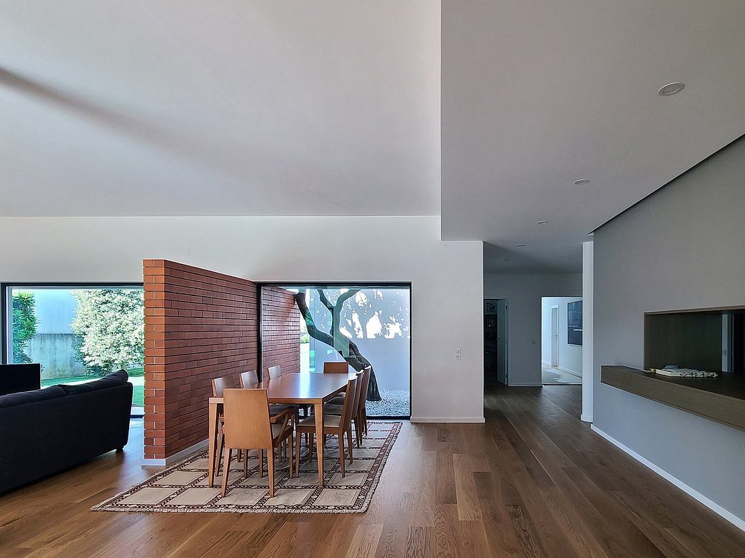 Spacious open-concept living area with wooden flooring, brick accent wall, and large windows.