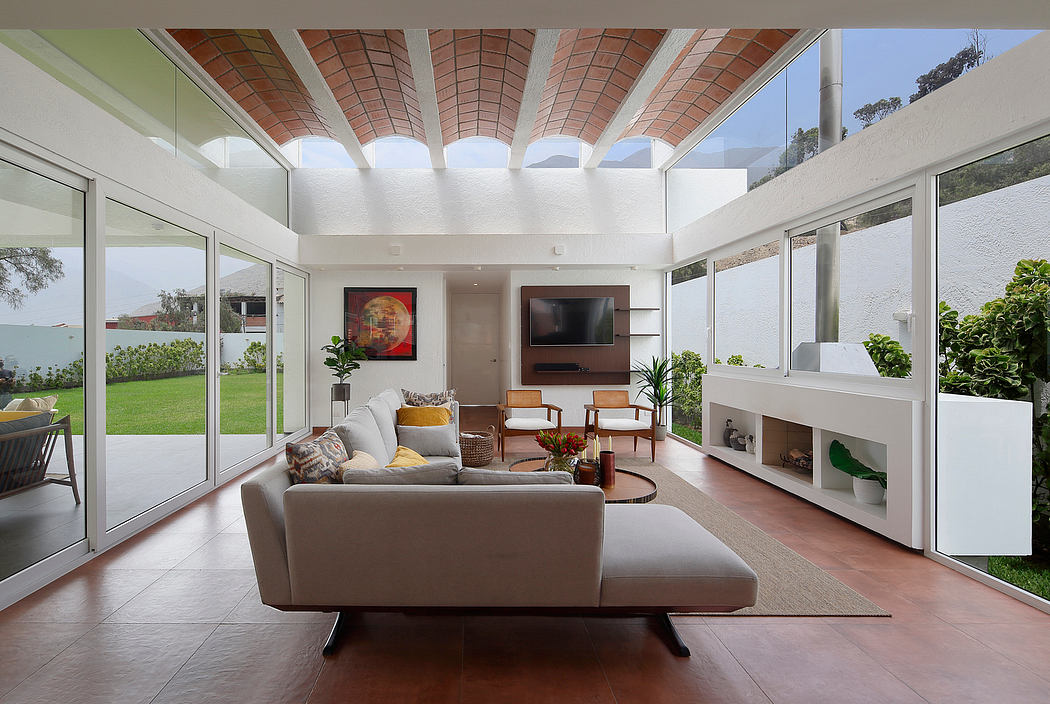 Spacious, open-concept living room with large windows, high ceilings, and exposed brick accents.