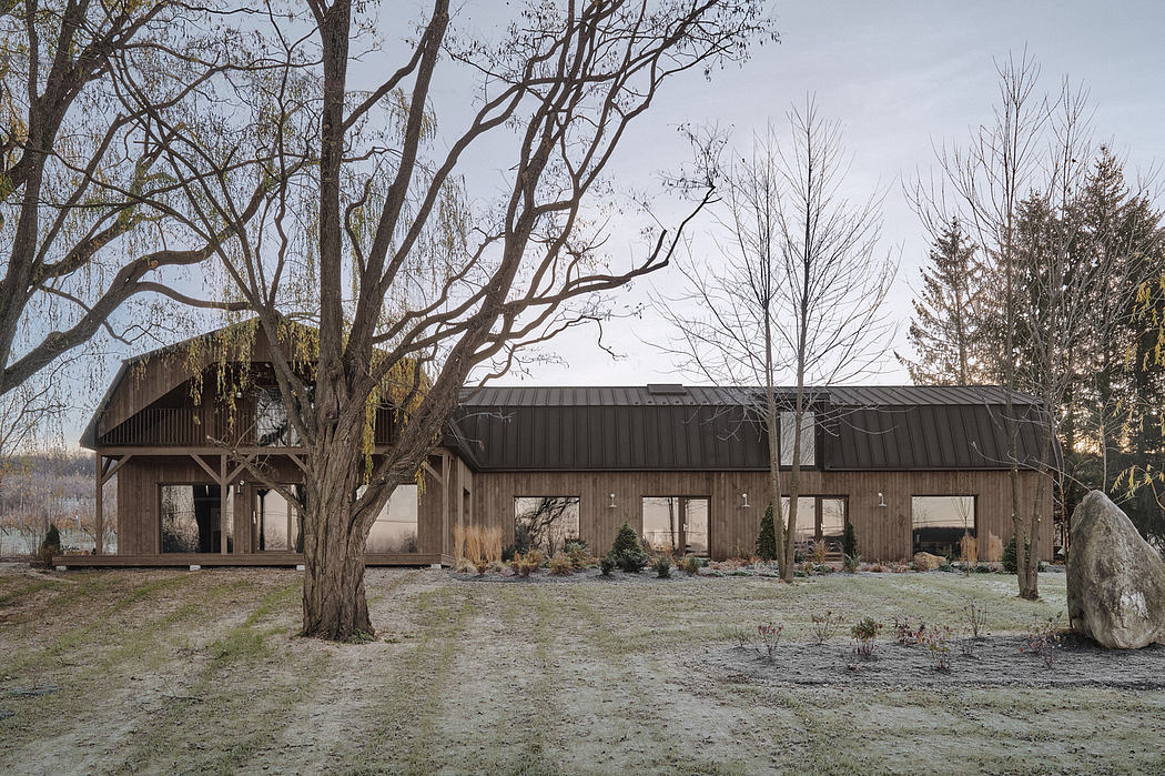 A rustic wooden building with a pitched roof and covered patio, surrounded by barren trees.