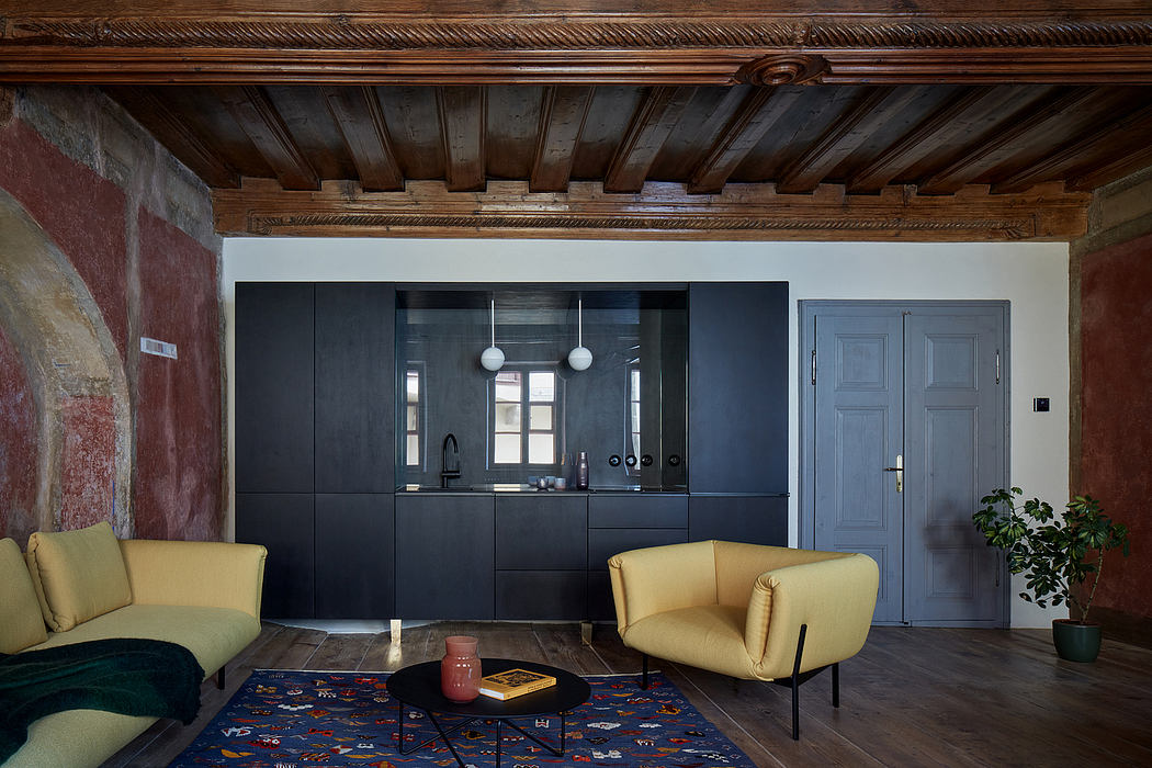 A cozy room with wooden beams, black cabinetry, and pops of color in the furniture.