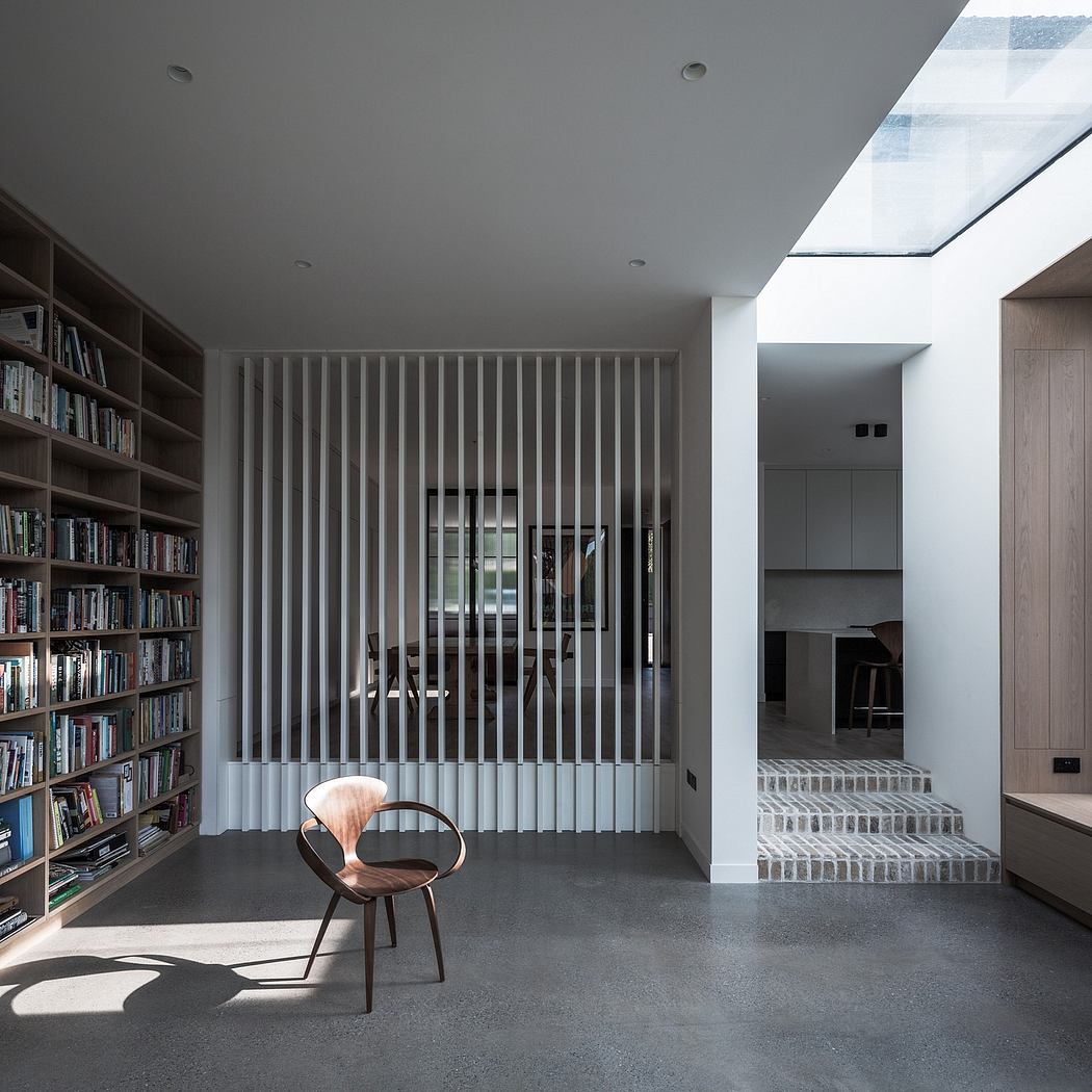 Minimalist living room with built-in bookshelves, wooden chair, and concrete flooring.