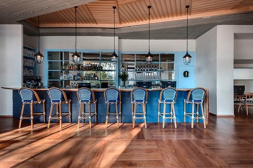 A cozy bar with a wooden ceiling, blue-and-white bistro chairs, and an elegant bar counter.
