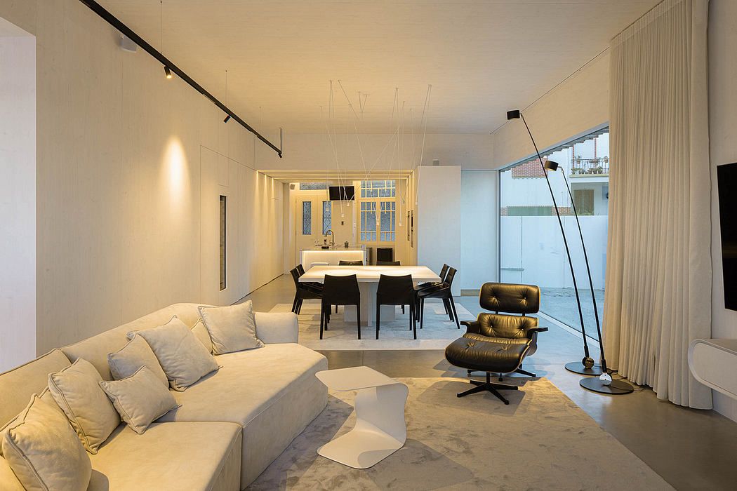 Minimalist living room with sleek furniture, track lighting, and expansive windows.